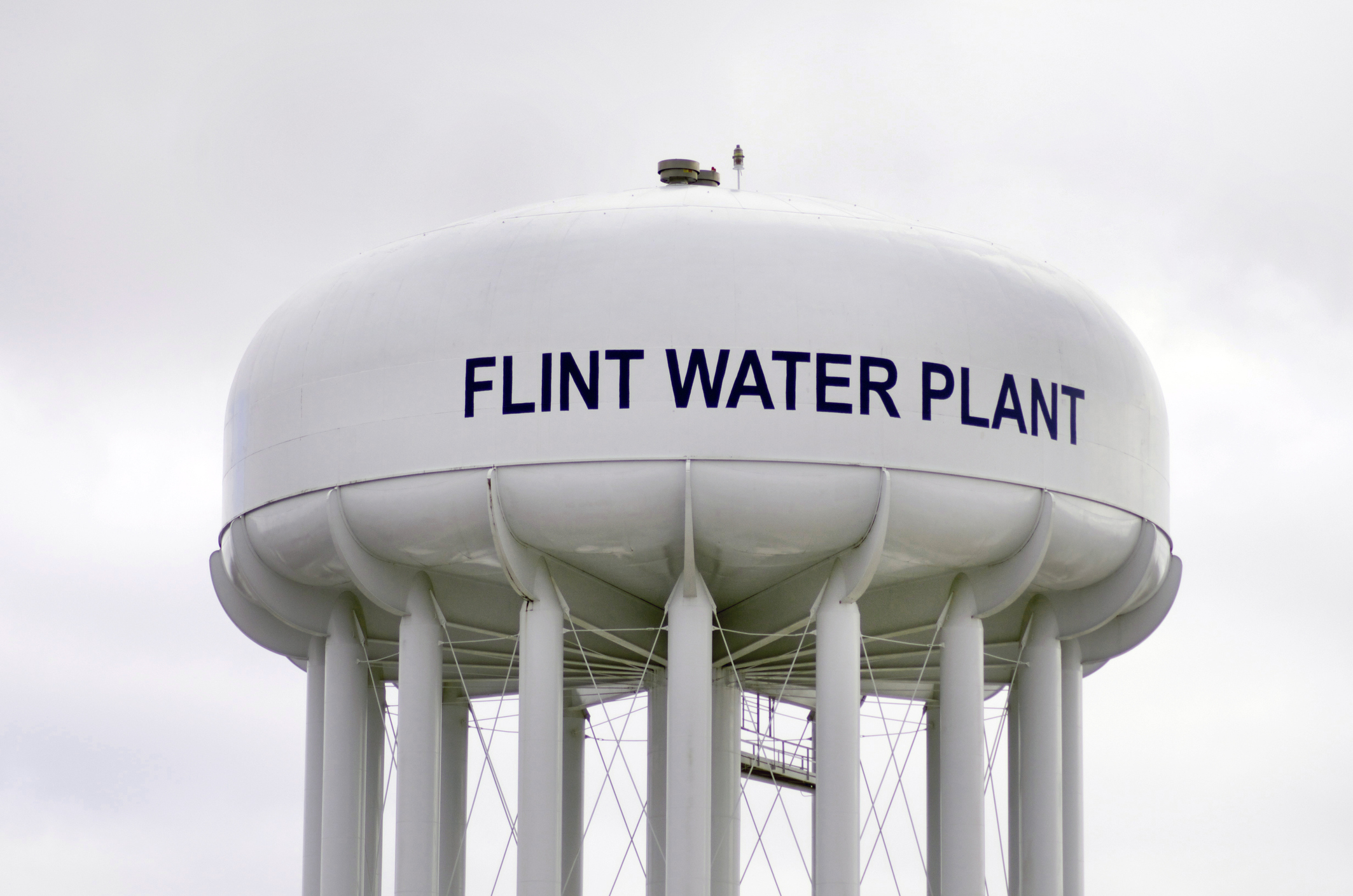 Photo of a large white water tower in Flint, Michigan with the text Flint Water Plant painted in black letters.