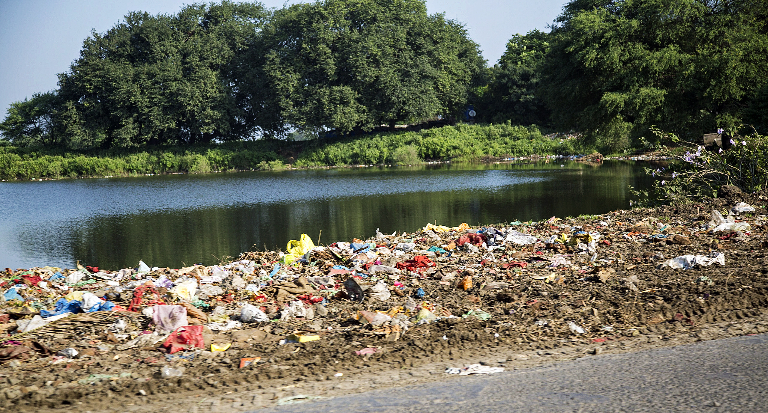 Large amounts of trash and pollution that has washed up on the on the bank of a river